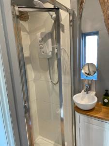 uma casa de banho com um chuveiro e um lavatório. em The Hat's Hut em Mixbury