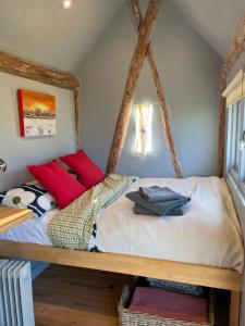 Un dormitorio con una cama con almohadas rojas. en The Hat's Hut, en Mixbury