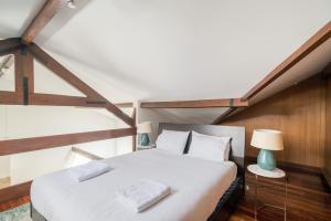 una camera da letto con un grande letto bianco in mansarda di PedrasNegras30 Lisbon Lofts & Apartments a Lisbona