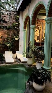 a swimming pool with white chairs and columns at Casa Verde Hotel in Santa Marta