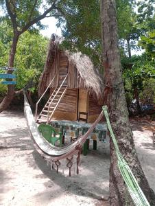 a hammock in front of a tree with a hut at Cabana juriti in Camaçari