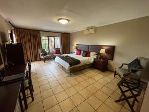 um quarto de hotel com uma cama e uma cadeira em Edelweiss Corporate Guest House em Pretoria