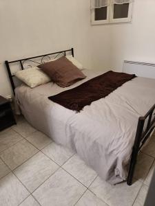 uma cama com lençóis brancos e almofadas castanhas em BEAU SOLEIL em Amélie-les-Bains-Palalda