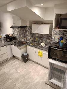 uma cozinha com armários brancos e um lavatório em BEAU SOLEIL em Amélie-les-Bains-Palalda