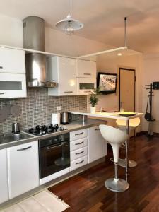 uma cozinha com armários brancos, uma mesa e um fogão em Casa La Mo’ moderno bilocale in zona tranquilla em Cattolica