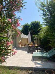 un patio con mesa, sombrilla y sillas en La Poétique - Air-conditioned house with 3 bedrooms!, en Montpellier