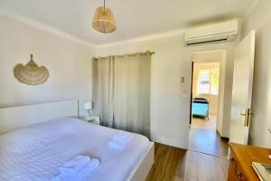 a white bedroom with a bed and a bathroom at La Poétique - Air-conditioned house with 3 bedrooms! in Montpellier