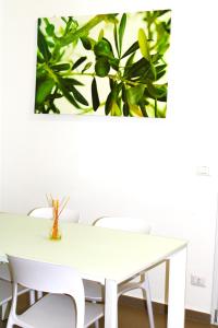 einen weißen Tisch mit Stühlen und ein Bild an der Wand in der Unterkunft Villa Costanza in Bari