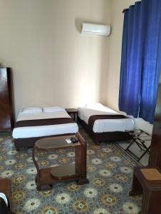 a hotel room with two beds and a table at La Casa del Turix in Mérida