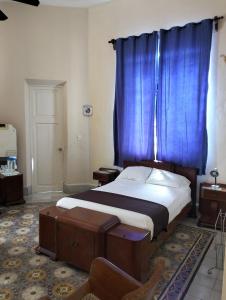 a bedroom with a bed with a blue curtain at La Casa del Turix in Mérida