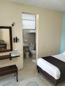 a bedroom with a bed and a bathroom with a toilet at La Casa del Turix in Mérida