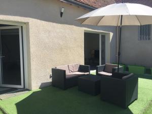 a patio with two chairs and an umbrella at La Grange du Pont in Civray-de-Touraine