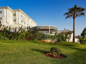 Villa Blanca Urban Hotel في الدار البيضاء: مبنى فيه نخلة وساحة عشبية