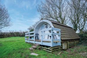 a small house with a roof on a field at The Pod - 1 Bedroom - Freshwest Beach Retreat in Pembroke