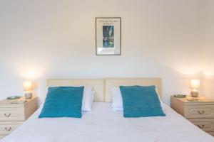 ein Schlafzimmer mit einem weißen Bett mit zwei blauen Kissen in der Unterkunft The Old Bakery in Southwold