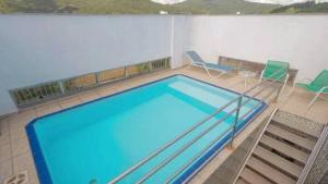 a large swimming pool in a room with chairs at Saint Sebastian Flat 206 - Com Hidro! até 4 pessoas, Duplex, no centro in Jaraguá do Sul