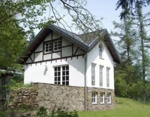 Casa blanca y negra con pared de piedra en Ferienhaus für 7 Personen und 1 Kind in Blankenheim, Eifel, en Blankenheim