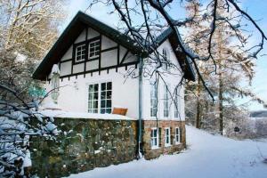 una casa blanca y negra en la nieve en Ferienhaus für 7 Personen und 1 Kind in Blankenheim, Eifel, en Blankenheim