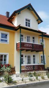 a yellow and white house with a balcony at Ferienwohnung Rose - b47219 in Peißenberg