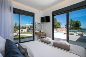 a bedroom with a large bed and large windows at Ocean Pearl Sea View in Faliraki