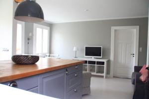uma cozinha com um balcão e uma televisão num quarto em "Weißes Haus" 9123II - Fehmarn em Fehmarn