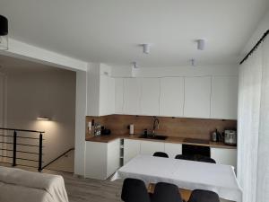 cocina con armarios blancos y mesa blanca en Leszka Loft Apartment, en Wodzisław Śląski