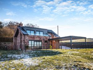 a brick house with a fence in front of it at The Bungalow in Rushton Spencer