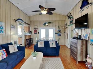 a living room with a blue couch and a ceiling fan at Flip Flop Beachside in Galveston