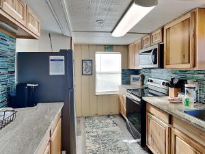 - une cuisine avec des placards en bois et un réfrigérateur noir dans l'établissement Flip Flop Beachside, à Galveston