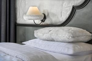 1 cama con almohada blanca y lámpara en Bio Hotel Hermitage, en Madonna di Campiglio