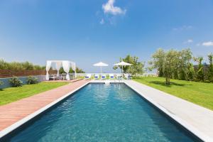 a pool in a backyard with a deck and lawn at Vilana Exclusive Villas in Skouloúfia