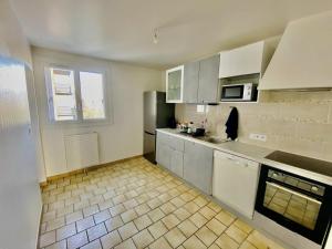 cocina con armarios blancos y suelo de baldosa en Appartement T3 de Standing en Centre-Ville, en Joué-lès-Tours