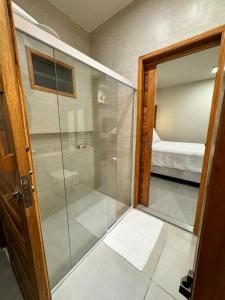 Una ducha de cristal en una habitación con dormitorio en POUSADA PONTA DA ASA en Coruripe