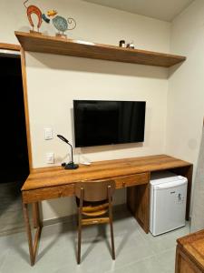 a wooden desk with a television on a wall at POUSADA PONTA DA ASA in Coruripe