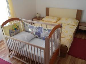 a baby crib in a room with a bed at Apartment Karla in Jadrtovac