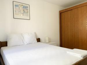 a bedroom with a white bed and a wooden door at Le Mainvillois - Parking Included in Mainvilliers