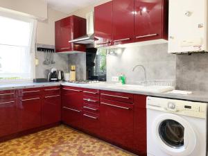 een keuken met rode kasten en een wasmachine bij Le Mainvillois - Parking Included in Mainvilliers