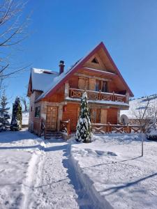 une cabane en rondins dans la neige avec une allée dans l'établissement Holiday Home Vile Calimero, à Žabljak