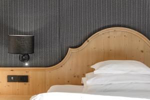 a bedroom with a bed with a wooden headboard at Bio Hotel Hermitage in Madonna di Campiglio