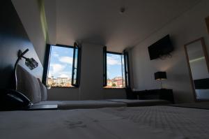 a bedroom with two beds and two windows at Hotel Vitória in Coimbra