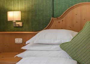 a bedroom with a bed with a headboard and a lamp at Bio Hotel Hermitage in Madonna di Campiglio