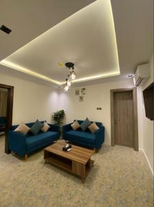 a living room with two blue couches and a coffee table at SUN SET HOTEL فندق سن ست in Najran