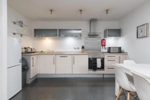 cocina blanca con armarios blancos y mesa en City Stay Apartments - Vizion, en Milton Keynes