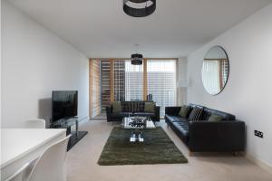 ein Wohnzimmer mit einem schwarzen Sofa und einem TV in der Unterkunft City Stay Apartments - Vizion in Milton Keynes
