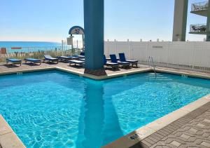 a large swimming pool with chairs and the ocean at Grandview East 702 in Panama City Beach