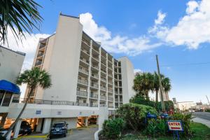 a large white building with palm trees in front of it at AquaVista Resort 805-W By Book That Condo in Panama City Beach
