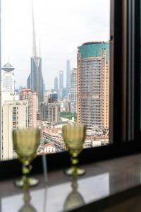 due bicchieri da vino seduti su un tavolo di fronte a una finestra di Shanghai Yi DU Apartments Downtown - near Nanjing West Road subway a Shanghai