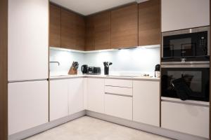 una cocina con armarios blancos y electrodomésticos negros en Newly Furnished Apt w/ Patios - Hampstead Heath en Londres