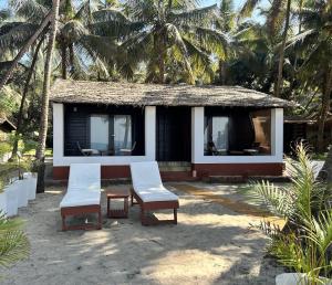 a small house with two chairs and a table at Mamagoa Beach Resort in Mandrem