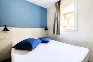 a bedroom with a white bed with blue pillows at Location Appartement Arzon (56640) 4 personnes in Arzon